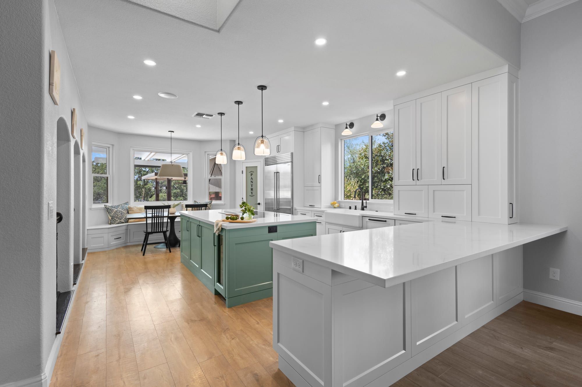 Remodeled white shaker kitchen with sage green island, quartz counters and oak floors